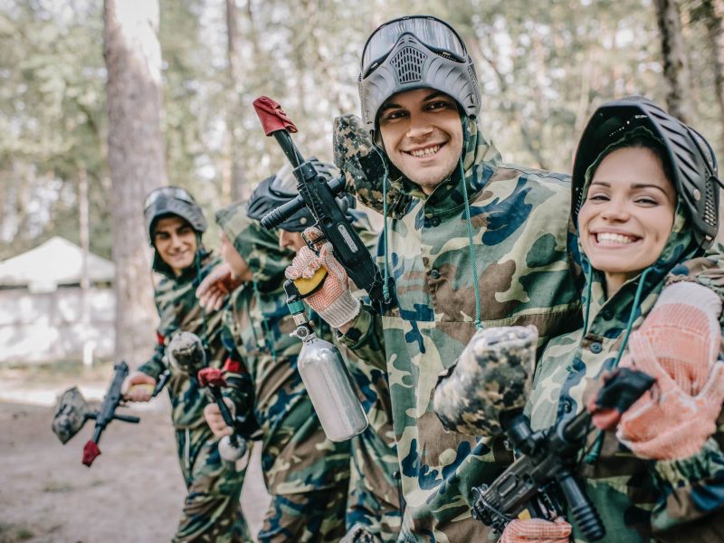 smiling young male paintballer embracing female teammate in camo